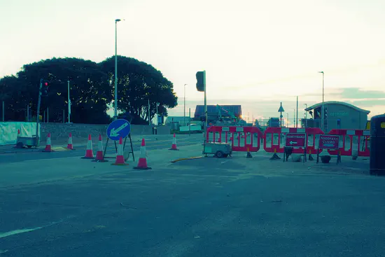 A photograph of Exmouth seafront with barriers across the footpath and signs indicating it's closed.