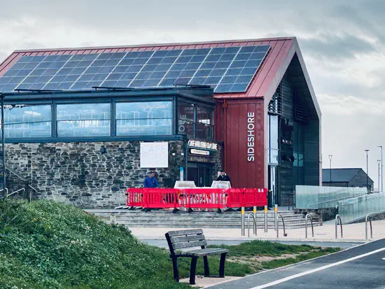 A photograph of the old Mickey's Beach Bar and Restaurant at Sideshore on Exmouth seafront. There's a temporary barrier across the entrance, and a skip being filled by two workers.